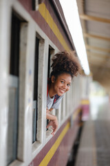 Happy Black Female heads out of Train window looking To Boyfriend, Cheerful Young African American Woman Greeting Her Husband After Arrival At Railway Station, Selective Focus On Lady.