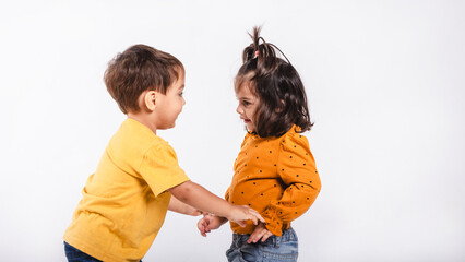 Two little children intending to hug each other in a studio shot on white background