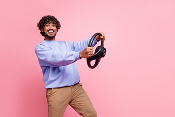 Photo portrait of nice young guy hold steering wheel hurry shopping wear trendy blue outfit isolated on pink color background