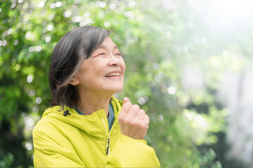 Close-up of the upper body of an elderly woman walking and running in a park amidst fresh greenery...