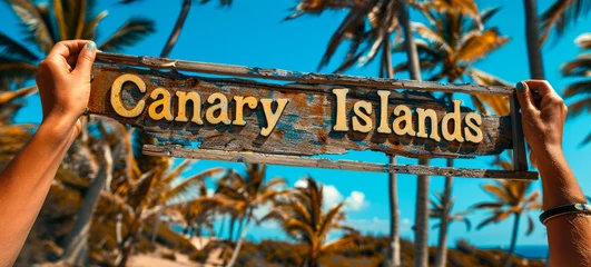 Photo sur Aluminium les îles Canaries Hands holding a rustic Canary Islands sign against a backdrop of vibrant palm trees, capturing the essence of a tropical paradise destination