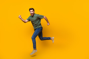 Fototapeta na wymiar Full body photo of attractive young man running fast have fun dressed stylish khaki clothes isolated on yellow color background