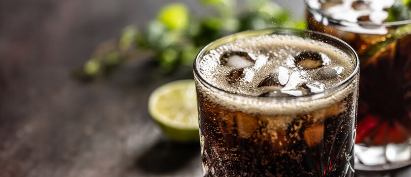 Bubbling Coke drink with ice cubes on the bar counter.