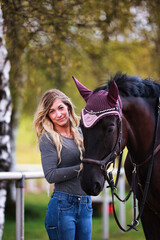 Obraz premium Young woman with long hair and blonde streaks, stands portraits with her horse.