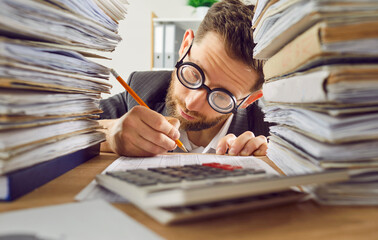 Close up portrait of funny tired concentrated business man accountant in suit and glasses working...