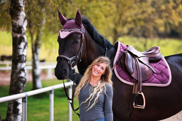 Young woman with long hair and blonde streaks, stands portraits with her horse.