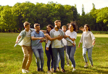 Portrait of a group of happy laughing people friends hugging in the summer park and smiling. Young smiling students having fun in nature outdoors. Friendship and togetherness concept.