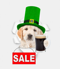 Saint Patrick's Day concept. Cute Golden retriever puppy wearing green hat of the leprechaun looks...