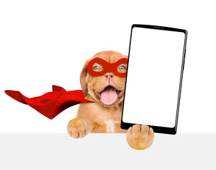 Happy Mastiff puppy wearing superhero costume shows big smartphone with white blank screen in it...