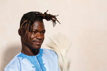 confident african man in traditional attire with horsehair fan