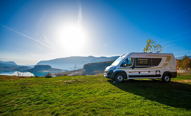 Fototapeta premium Campervan, Motorhome RV parked next&nbsp;to the lake or river in Bosnia and Herzegovina. Travelers with camper&nbsp;van&nbsp;or motor&nbsp;home are resting on an active family vacation on a road trip to Ramsko lake.&nbsp;&nbsp;