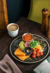 English Breakfast served on a black ceramic plate. Wooden table. Top view