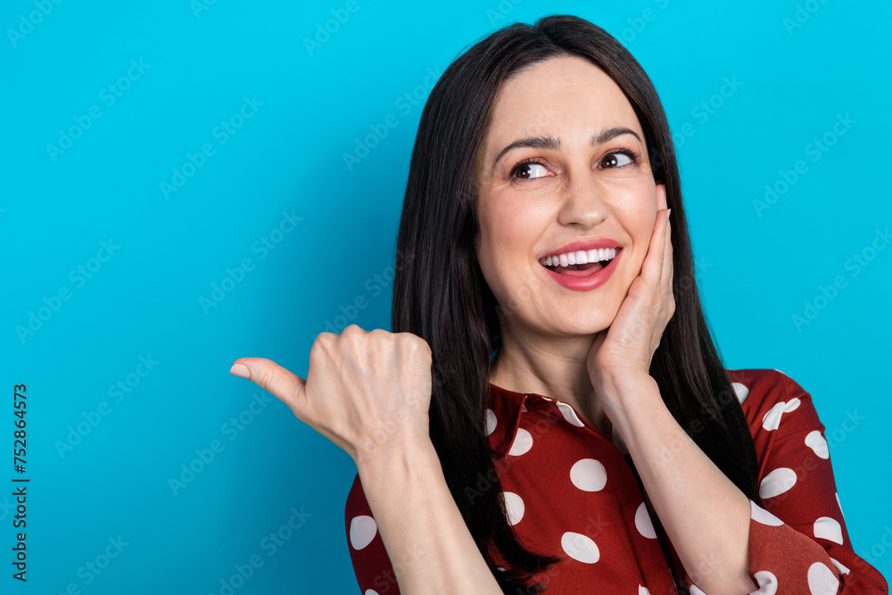 Sticker Portrait of charming impressed girl wear red shirt indicating look at sale empty space palm on cheekbone isolated on blue color background