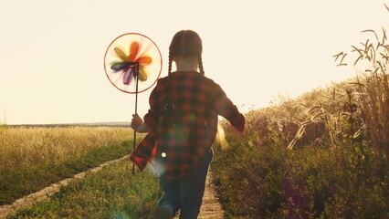 the pinwheel begins to play, child kid runs through park windmill hands, smile face, hand spinning...