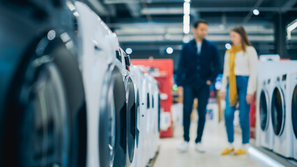 Multicultural Couple Evaluates Washing Machine Choices at Home Electronics Store. Man and Woman in...