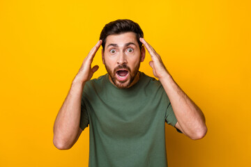 Photo of impressed funky man wear khaki t-shirt arms head open mouth isolated yellow color...