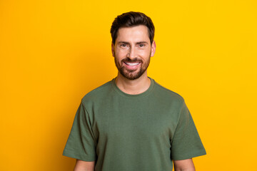 Photo of cheerful positive guy dressed green t-shirt smiling empty space isolated yellow color...