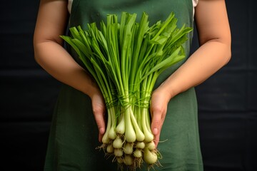 
Photo of a female hand holding a bunch of fresh Sweet Garleek, a hybrid of garlic and leeks, showcasing its vibrant green stalks and bulbous cloves - obrazy, fototapety, plakaty