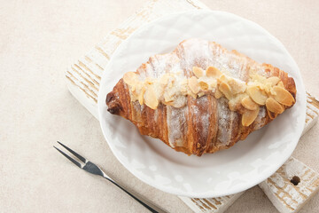 Almond Croissant with sprinkling icing sugar on white plate 
