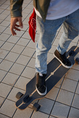 Closeup hipster man riding skateboard, focus on foot wearing sneakers