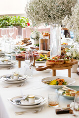 Served wedding table with decorative fresh white gypsophila flowers. Celebration details. Flower composition in plates. Serving food. Wedding decorations