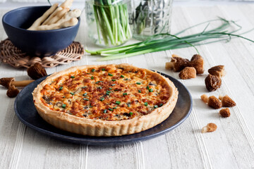 Quiche - a tart pie with spring morel mushrooms, onion and cheese on a plate