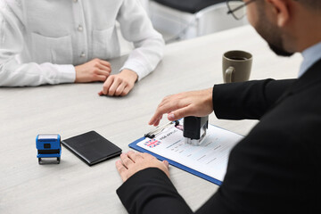 Immigration to United Kingdom. Embassy worker approving visa application form to woman in office, closeup