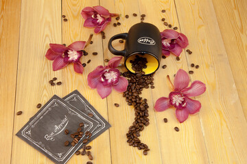 Scattered coffee beans. a cup of black coffee, espresso. orchid flowers. Traditional hospitality and care. (the inscription on the 