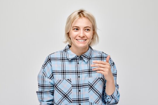 Portrait of a smiling young woman in a plaid shirt, posing against a light grey background.