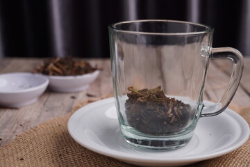 dried tea leaves in clear glass with saucer as base on wooden table