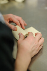 Close-up of baker's hands, bakery and pastry concept. Professional pastry chef making chocolate roll.