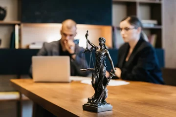 Fotobehang A lawyer meets with a new client. A young male lawyer in a suit sits at an office desk, shares legal advice, explains the inheritance process, tries to help. Legal advice concept © Vladislav