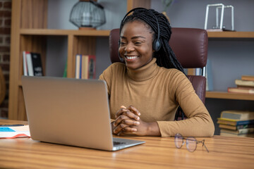 Woman with dreadlocks in headphones provides virtual training for students using laptop