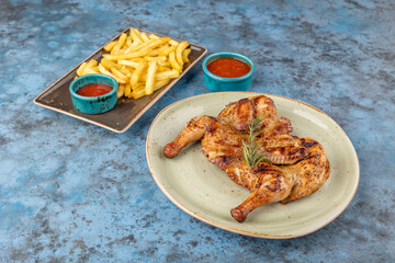 Grilled fried roast Chicken Tabaka, french fries and ketchup on plates on blue background.