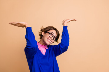 Photo of struggling hardworking girl look up arms palms hold heavy empty space isolated on beige...