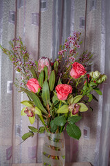 A bouquet of lilies, roses and dried flowers, standing on a beautiful background
