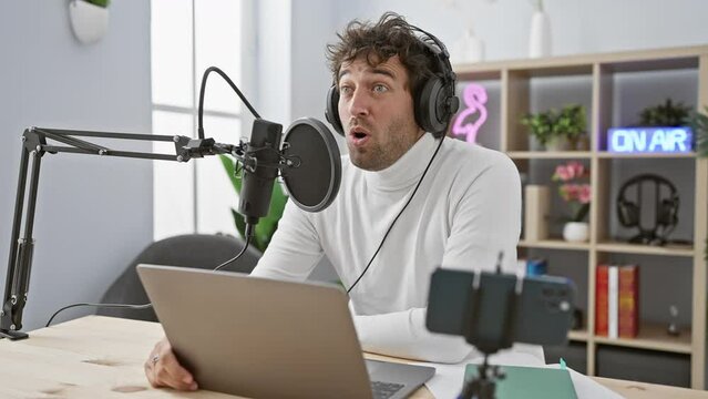 Young hispanic chap in shock, mouth agape in disbelief at a radio studio! amazed, headphones on, the scared look on his face says it all