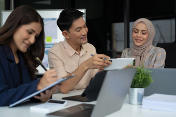 Asian businessman showing hand and smiling young team of colleagues making good business discussion in modern coworking office concept teamwork people.