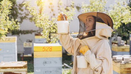 Happy smiling female beekeeper holding ready organic honey made in bee farm