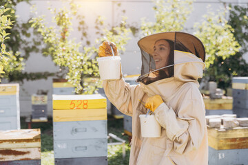 Happy smiling female beekeeper holding ready organic honey made in bee farm