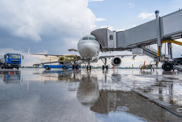 Airplane at the airport. Passengers board through a telescopic gangway. Loading luggage. Preparing for the flight. Handling service plane. Rain