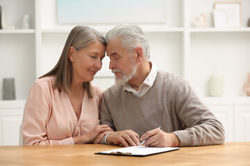 Senior couple signing Last Will and Testament indoors