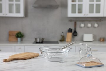 Whisk, bowl, board and other kitchen utensils on white marble table indoors, space for text