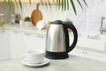 Electric kettle and cup on table in kitchen