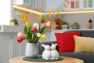 Easter decorations. Bouquet of tulips and bunny figures on table indoors