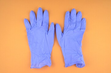 Obraz premium Two blue latex medic (medical) gloves on an orange background