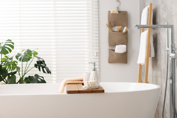 Set of different bath accessories and soap on tub in bathroom