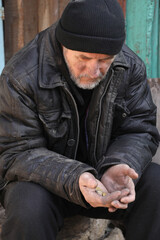 Fototapeta premium Poor homeless senior man holding coins outdoors