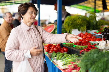 Elderly woman buys vegetables at an open air market
