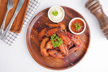 Cooked grilled chicken wings marinated with seasonings Placed on an old wooden tray on a white...